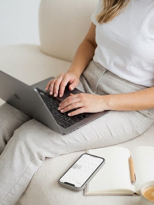 Website-Betreuung: Webdesignerin arbeitet am Laptop, daneben Smartphone mit Kalender für regelmäßige Wartungstermine